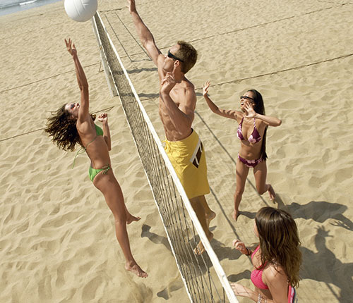 Swingers playing volleyball on beach